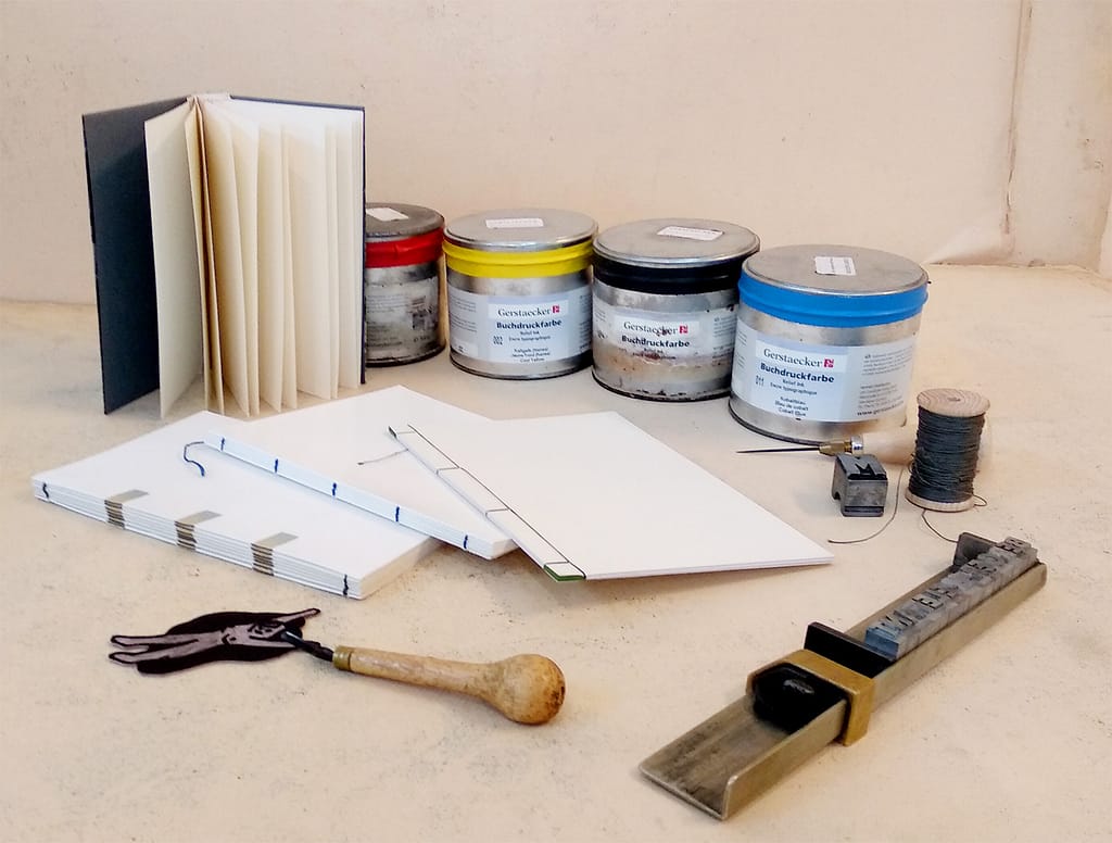 4 bound booklets, tools for linocut and book binding, and letterpress inks